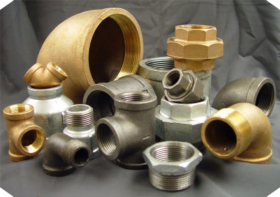 Assortment of brass, black, and galvanized threaded pipe fittings including elbows, tees, unions, and couplings